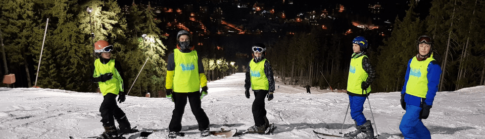 Kindergruppe auf Piste beim Nachtskifahren