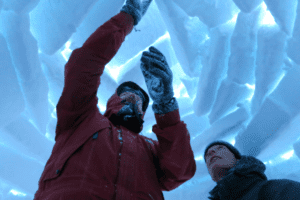 Mann baut Iglu im Outdoorkurs