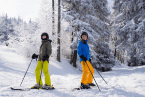 Zwei Kinder auf Skiern vor einem Wald