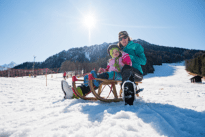 Muter mit Kind beim Rodeln