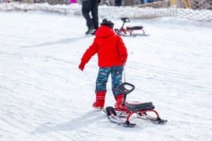 Kind zieht Schlitten hinter sich her beim Wintersport