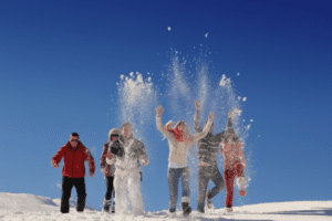 Jugendgruppe schmeißt Schnee in die Luft und springt