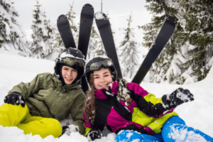 Zwei Jugendliche liegen im Schnee vor ihren Skiern