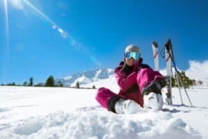Frau macht Pause neben ihren Skiern