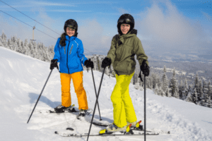 Junge und Mädchen auf Skiern lachen