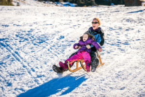 Mutter mit Kind auf dem Schlitten im Skiurlaub Bayerischer Wald