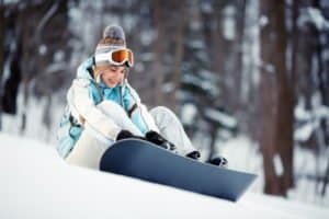 Mädchen schnallt sich Snowboard an
