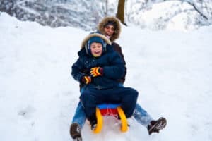 Rodeln Eltern mit Kind auf Winterreise