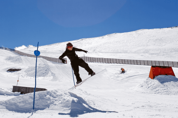 Junger Snowboarder springt über Rampe im Skigebiet Obertauern
