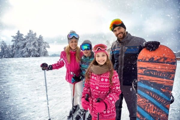 smiling family enjoying winter sports and vacation on snow in mountains