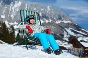 Kind im Skianzug liegt im Liegestuhl