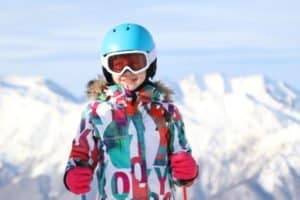 Kleines Mädchen lacht in Skiklamotten