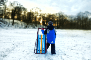 Kleiner Junge mit Schlitten