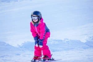 Mädchen in rosa Skiklamotten beim Bremsen