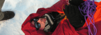 Mann in Rettungsdecke im Schnee