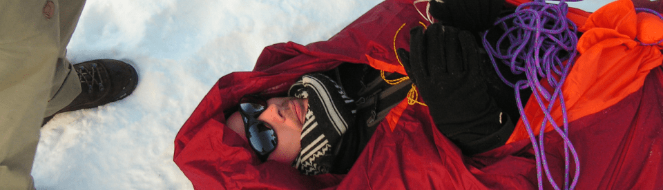 Mann in Rettungsdecke im Schnee