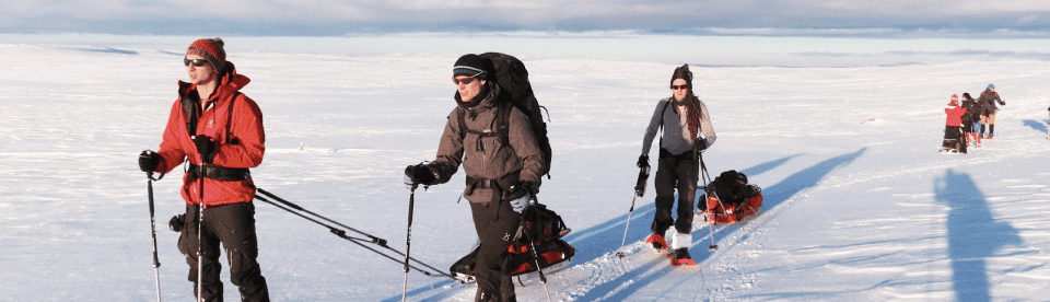 3 Personen mit Schneeschuhen und Schlitten