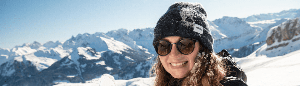 Frau lacht in Kamera mit Bergpanorama im Hintergrund