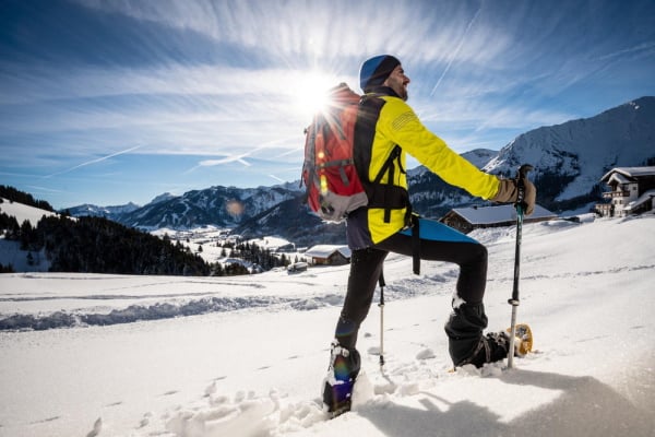 Mann steht mit Schneeschuhen im Schnee