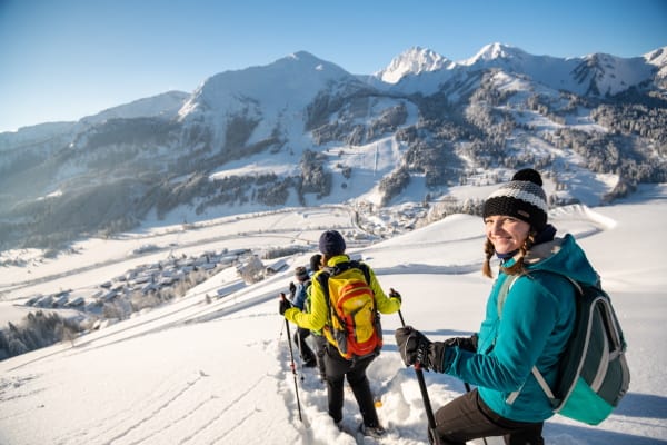 Gruppe beim Abstieg im Schnee und Frau schaut in die Kamera