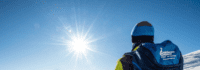 Person von hinten mit rucksack gegen die Sonne fotografiert