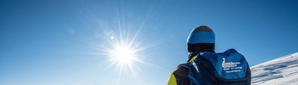 Person von hinten mit rucksack gegen die Sonne fotografiert