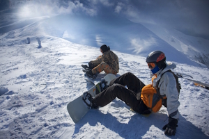 Zwei Snowboarder sitzen auf der Piste