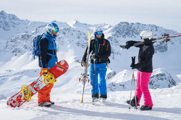Zwei Skifahrer und ein Snowboarder mit ihrer Ausrüstung im Single-Skiurlaub Arosa-Lenzerheide
