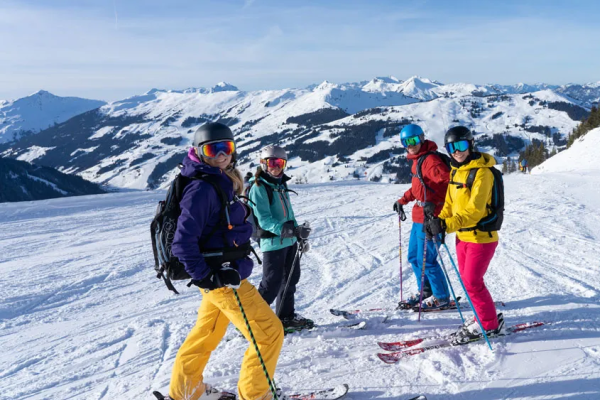 Vier Skifahrer stehen lachend auf der Piste im Single-Skiurlaub Saalbach-Hinterglemm