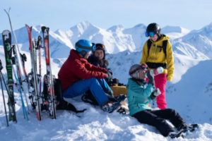 Vier Skifahrer pausieren auf der Piste ohne Skier