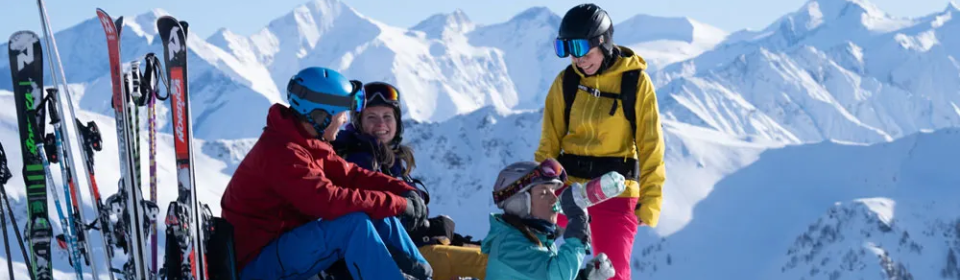 Vier Skifahrer machen Pause auf dem Gipfel