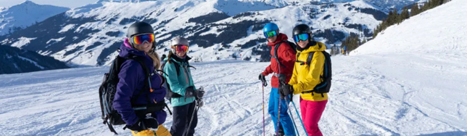 Vier Skifahrer warten lachend auf der Piste