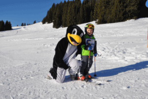 Kind mit Skiern und Pinguin auf der Familienfreizeit SaalbachS