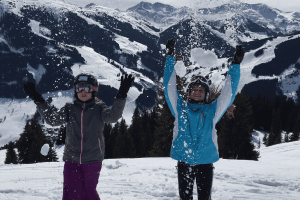 Kinder werfen Schnee in die Luft in der Skifreizeit Saalbach