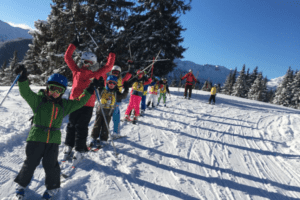 Skikurs hebt die Arme in die Luft