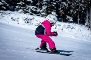 Kleines Mädchen in pink in der Abfahrtshocke